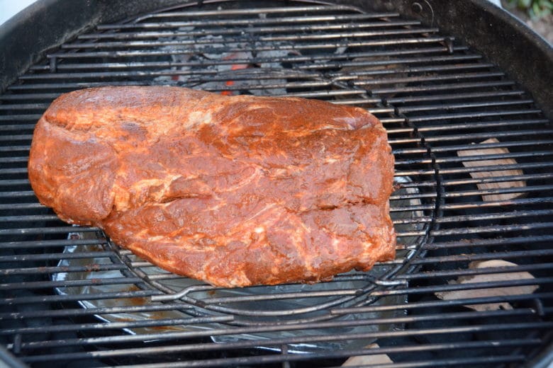 Pulled Pork beim Auflegen auf den Kugelgrill