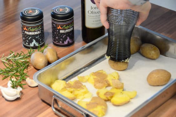 Die Kartoffeln mit einem Glas zu Stampfkartoffeln machen