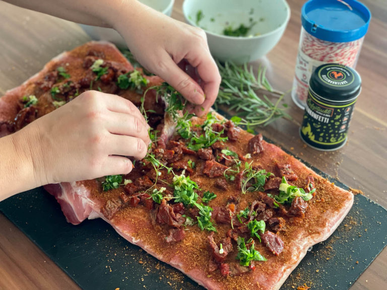 Den Rollbraten mit Gewürzen, Tomaten und frischen Kräutern füllen